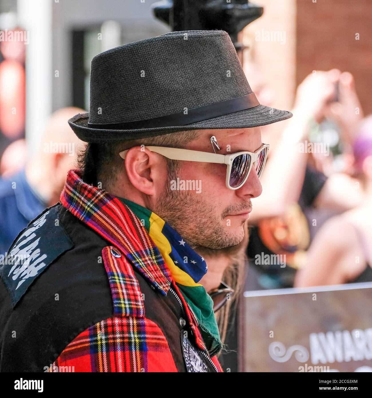 punk maschio con trinby, camicia di controllo e piercing viso con pin di sicurezza Foto Stock