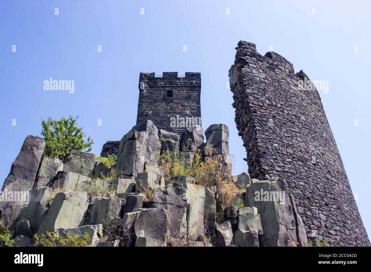 Ruines del castello di Hazmburk in cima alla cima della catena montuosa di ceske stredohori. Vista sulla torre bianca, le rocce e le pareti. Foto Stock