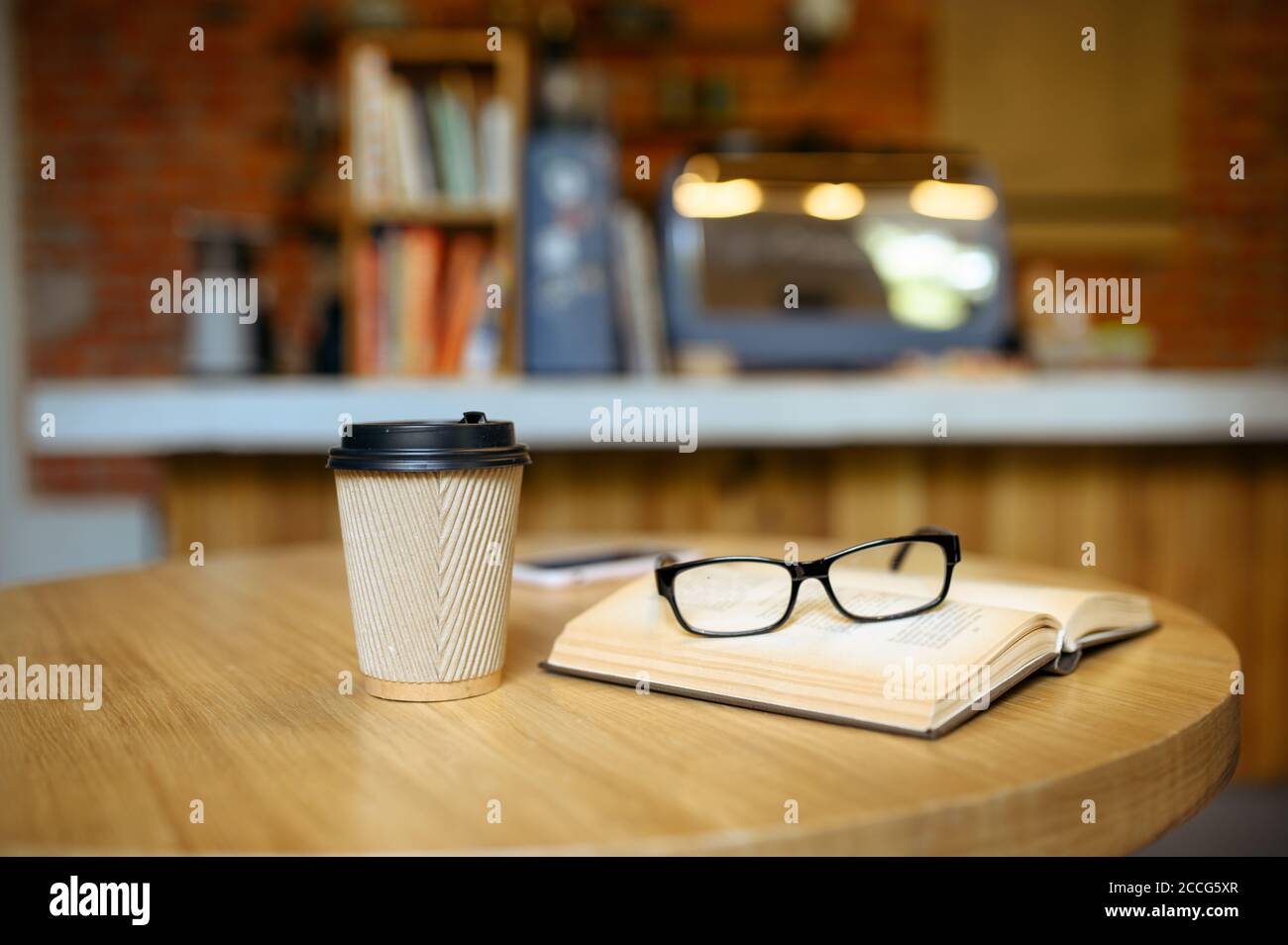 Libro, caffè e bicchieri sul tavolo nel cafe per studenti Foto Stock