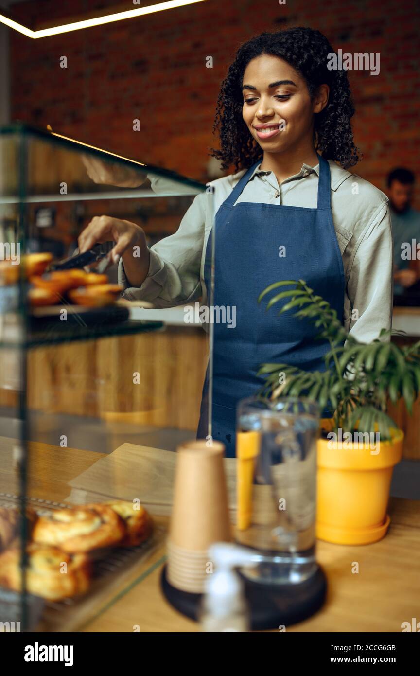 Il barista femminile tiene un piatto con croissant al caffè Foto Stock