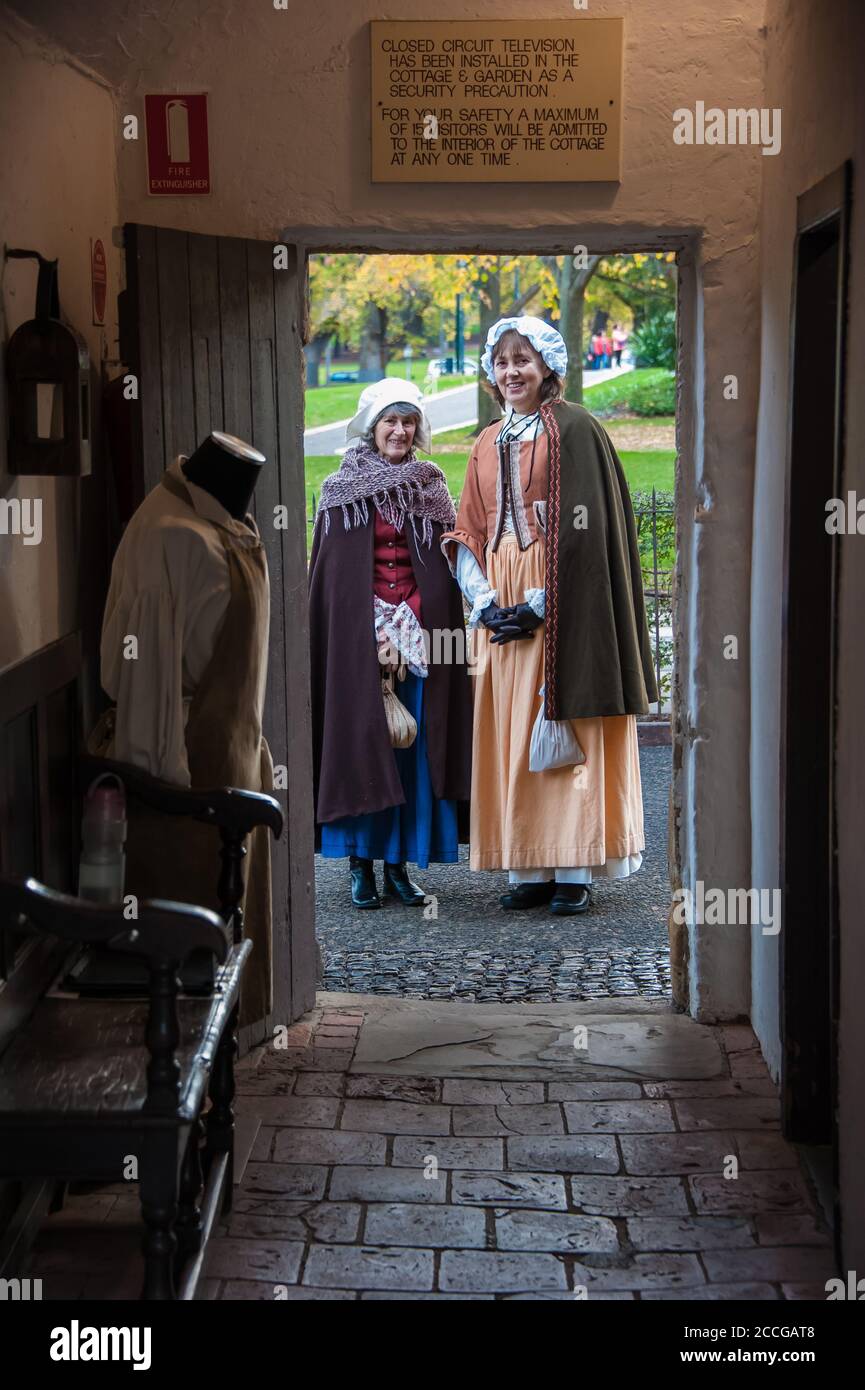 Captain Cook's Cottage guardando fuori la porta accanto a due donne in abiti d'epoca, una delle principali attrazioni turistiche a Fitzroy Gardens Melbourne, Australia Foto Stock