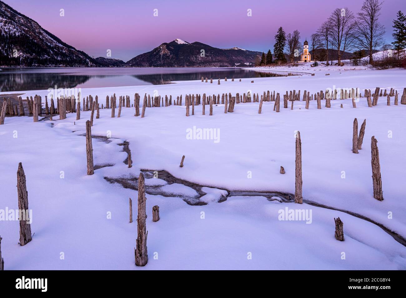 La piccola cappella di San Margareth, Jochberg sullo sfondo e in primo piano le antiche tavole di legno di una storica fattoria di pesce o gamberi su t Foto Stock