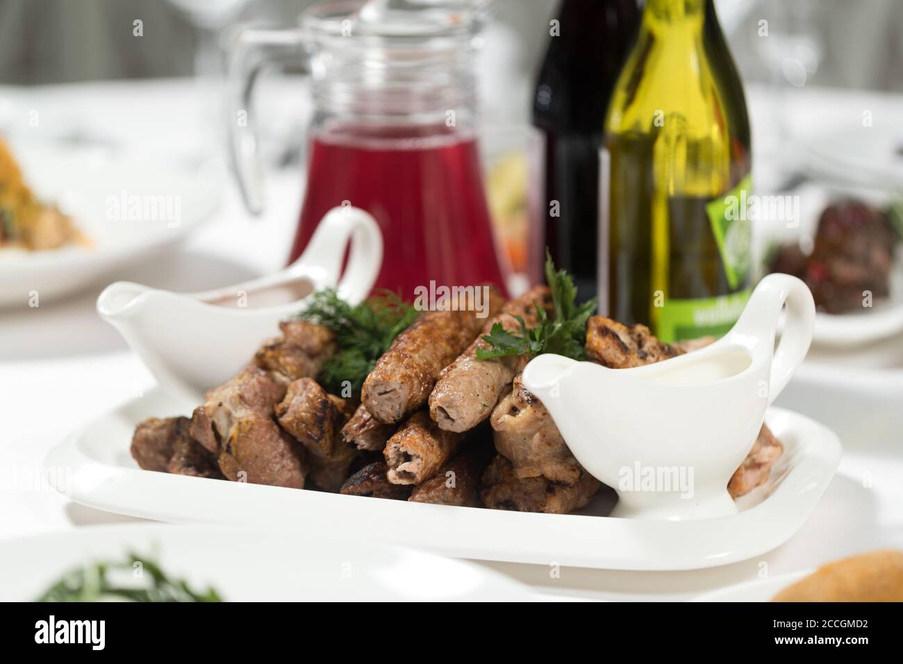 Kebab alla griglia, spiedini di pollo e maiale, salsa rossa e bianca su un piatto. Carne assortita. Piatti di carne. Banchetti, menu a buffet Foto Stock