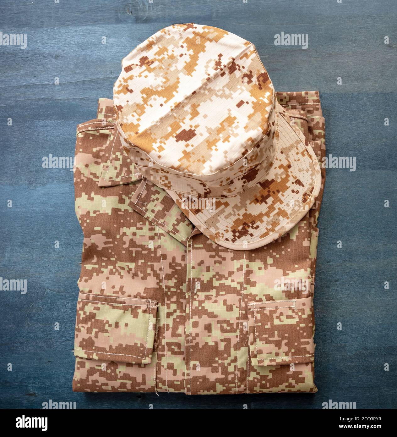 Cappellino dell'esercito DEGLI STATI UNITI su fondo di legno di colore blu e uniforme ripiegato. Camouflage militare con motivo digitale del deserto, camicia e capo outfit Foto Stock
