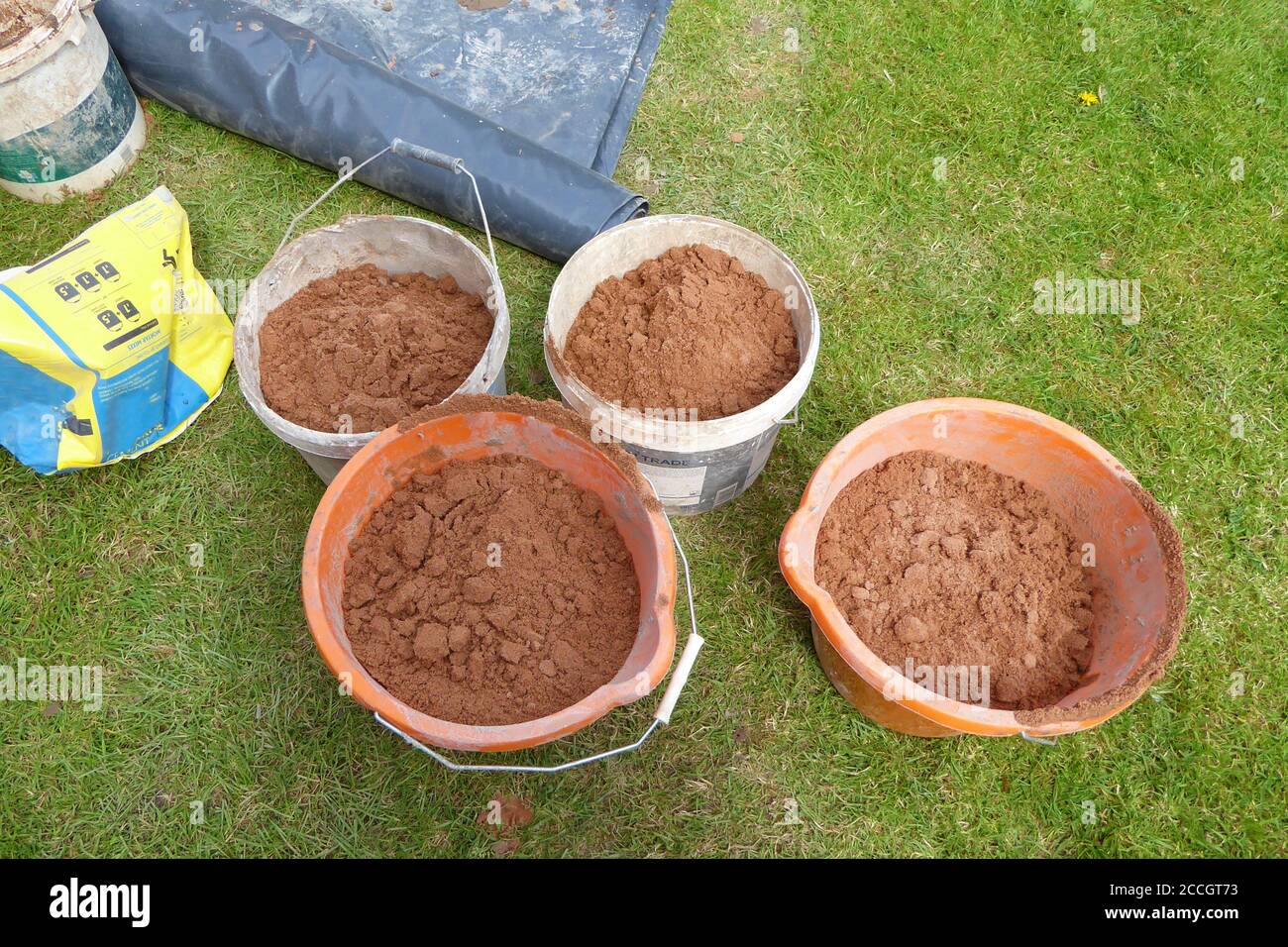 primo piano di 4 secchi di sabbia per costruire casa estensioni su erba fuori in estate Foto Stock