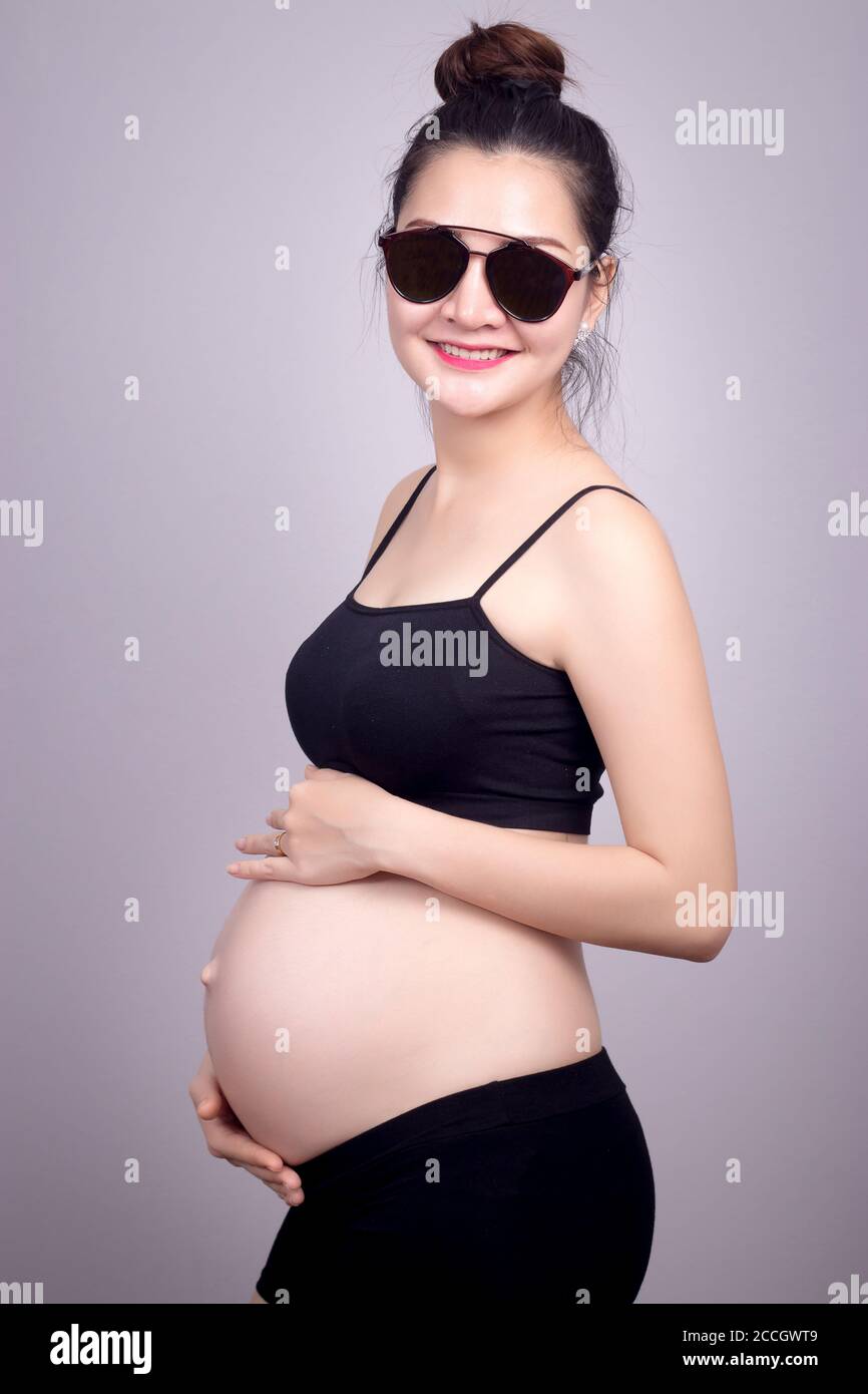 Happy MOM Concept : Ritratto di felice donna asiatica incinta con viso sorriso in abito nero con occhiali da sole. Bella Asia modello femminile nel suo 20s. Foto Stock