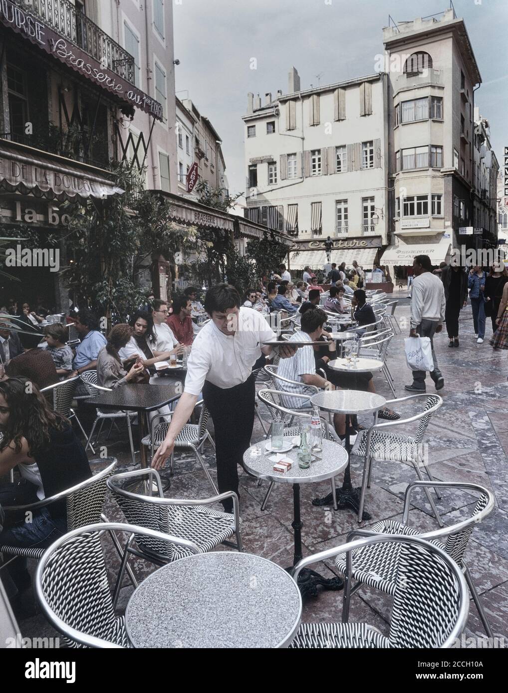 Caffè, brasserie e ristoranti sul marciapiede in Place de la Loge. Perpignan, Roussillon, dipartimento dei Pirenei Orientali, Francia. Circa anni '90 Foto Stock