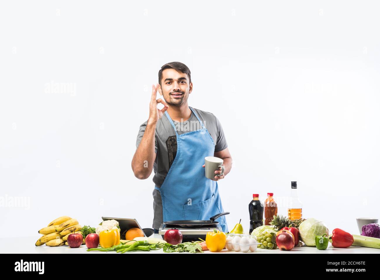 Uomo in grembiule e cappello da chef cucinare cibo in cucina. Bell'uomo che  cucina cibi