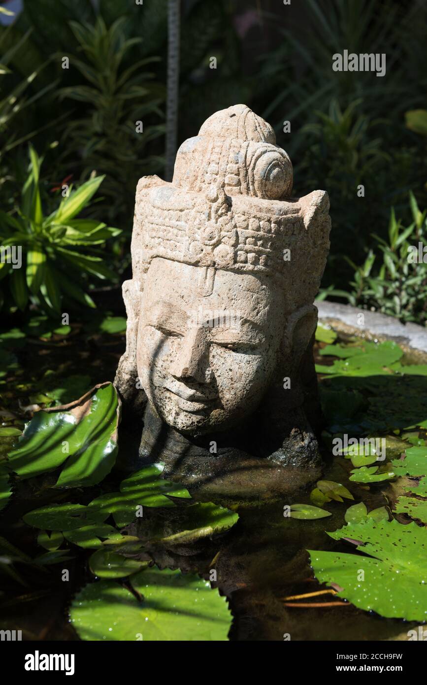 Balinese pietra scolpita testa in Lily Pond Foto Stock