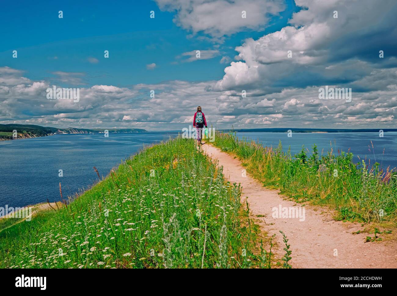 viaggiatore hipster ragazza con zaino esplorando verdi colline. Il mare blu intorno. Concetto di viaggio e wanderlust. Foto Stock