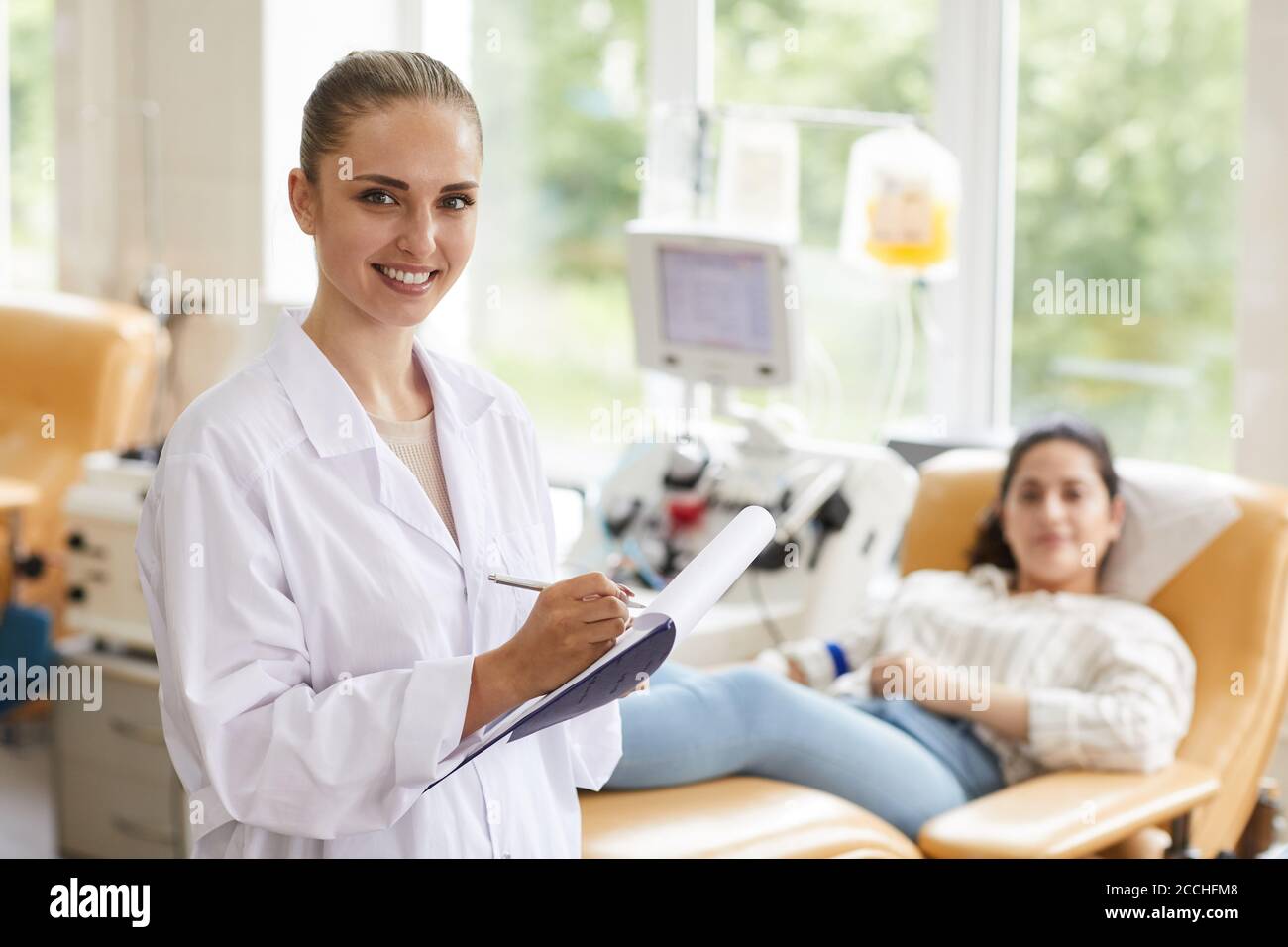Ritratto di una donna che sorride alla telecamera mentre esamina il paziente in ospedale Foto Stock