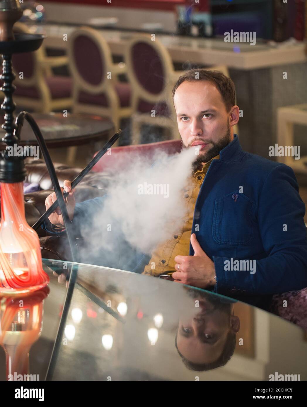 Fumare hookah in un caffè. L'uomo sta soffiando fumo. Foto Stock