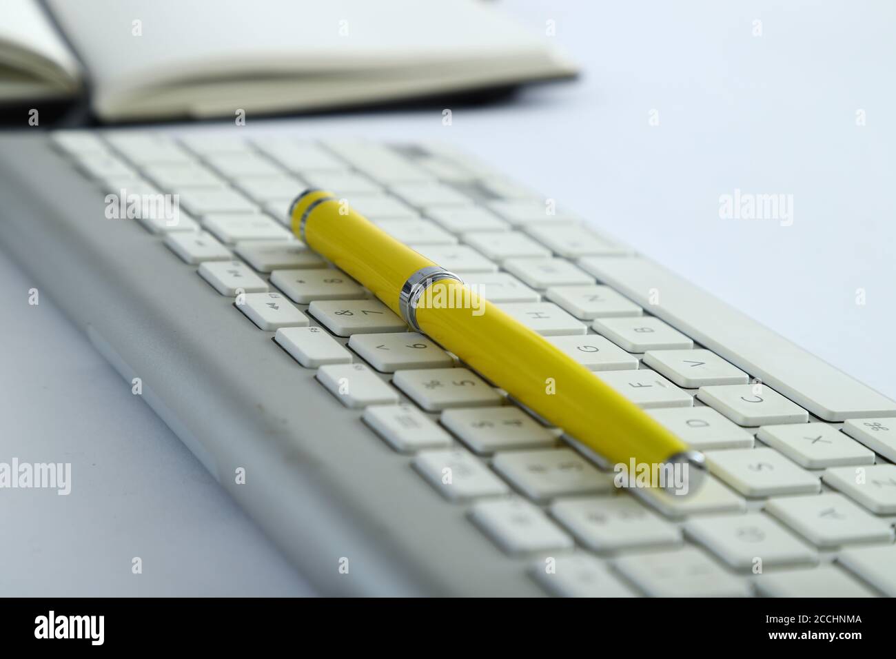 Tastiera in alluminio bianco con tavolo da ufficio con penna gialla Foto Stock