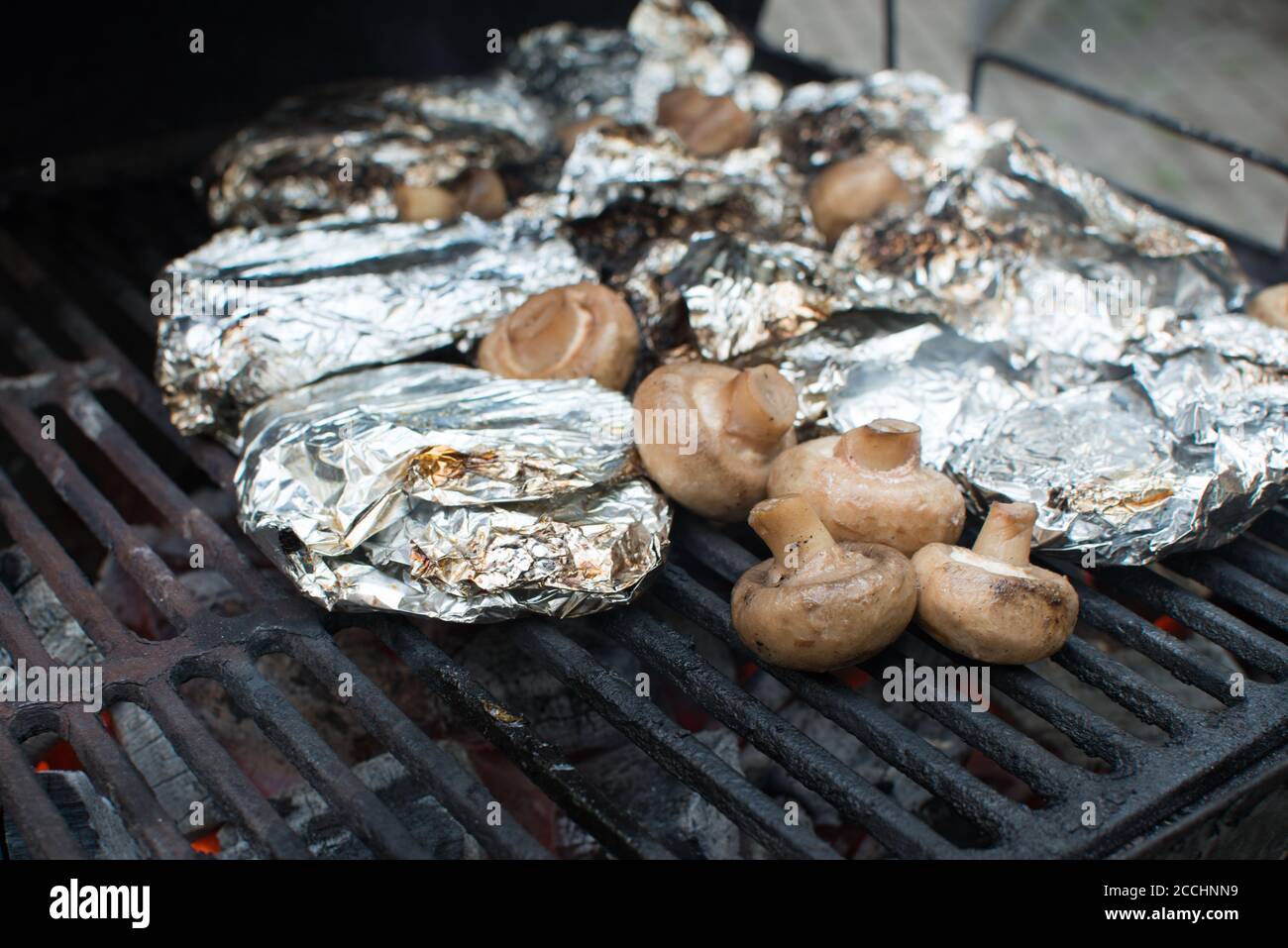 Funghi e carne nel foglio sulla griglia. Weekend e picnic Foto Stock