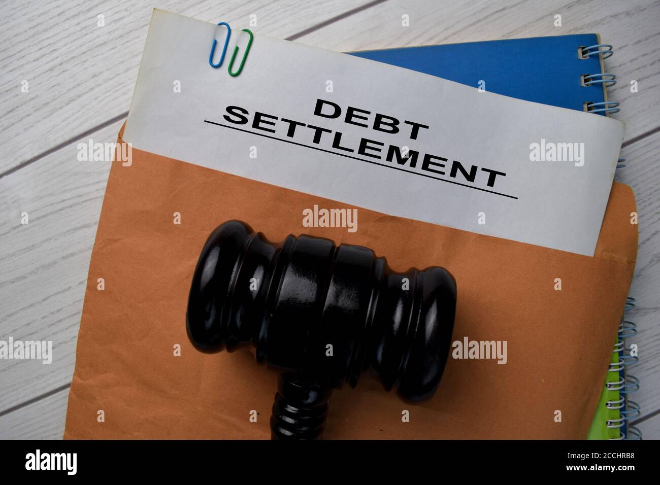 Testo di liquidazione del debito con busta marrone del documento e gavel isolato sulla scrivania dell'ufficio. Foto Stock