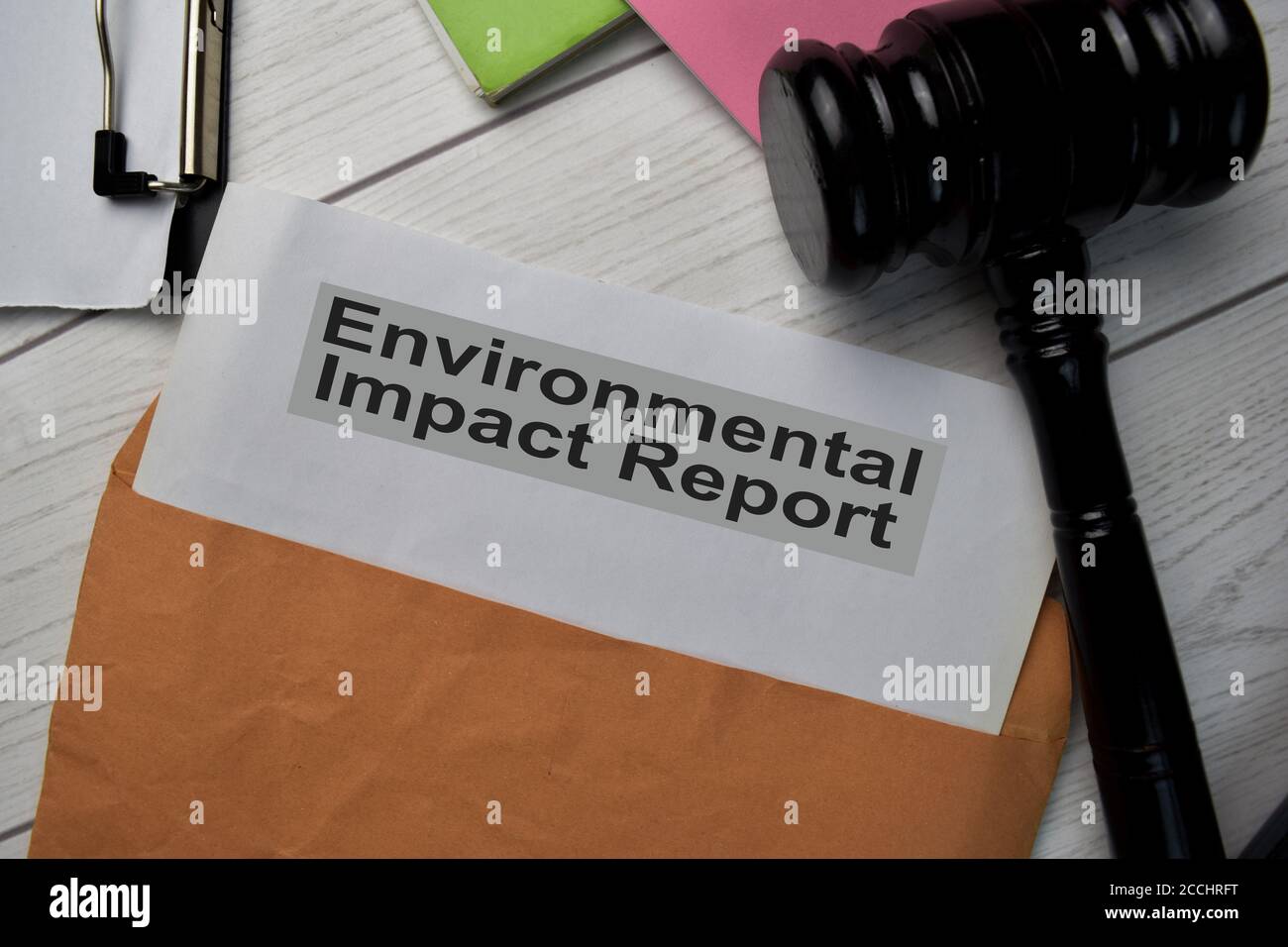 Testo del rapporto sull'impatto ambientale con busta marrone del documento e gavel isolati sulla scrivania dell'ufficio. Foto Stock