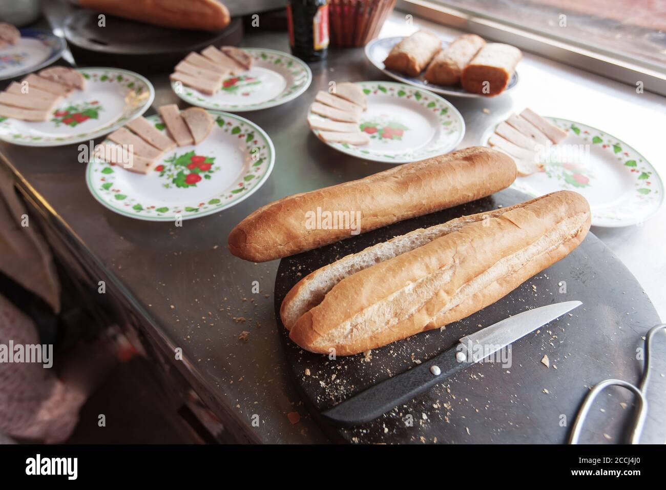 Primo piano di Baguette o pane francese con salsicce su tavolo di legno per cucinare in un ristorante locale Khmer. Koh Kong, Cambogia del Sud. Foto Stock