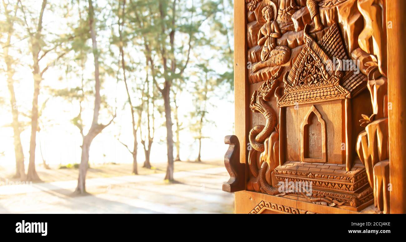 Finestra aperta del tempio buddista con spiaggia al tramonto sfocata sullo sfondo, modello di tempio buddista scolpito finestra in legno. Wat Khuan, Tailandia. Foto Stock