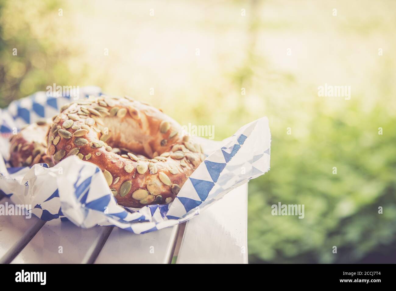 Pretzel bavaresi freschi per colazione, adagiati su un tavolo di legno all'aperto Foto Stock
