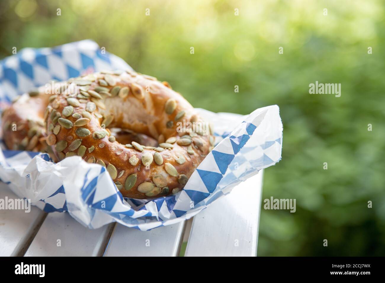 Pretzel bavaresi freschi per colazione, adagiati su un tavolo di legno all'aperto Foto Stock