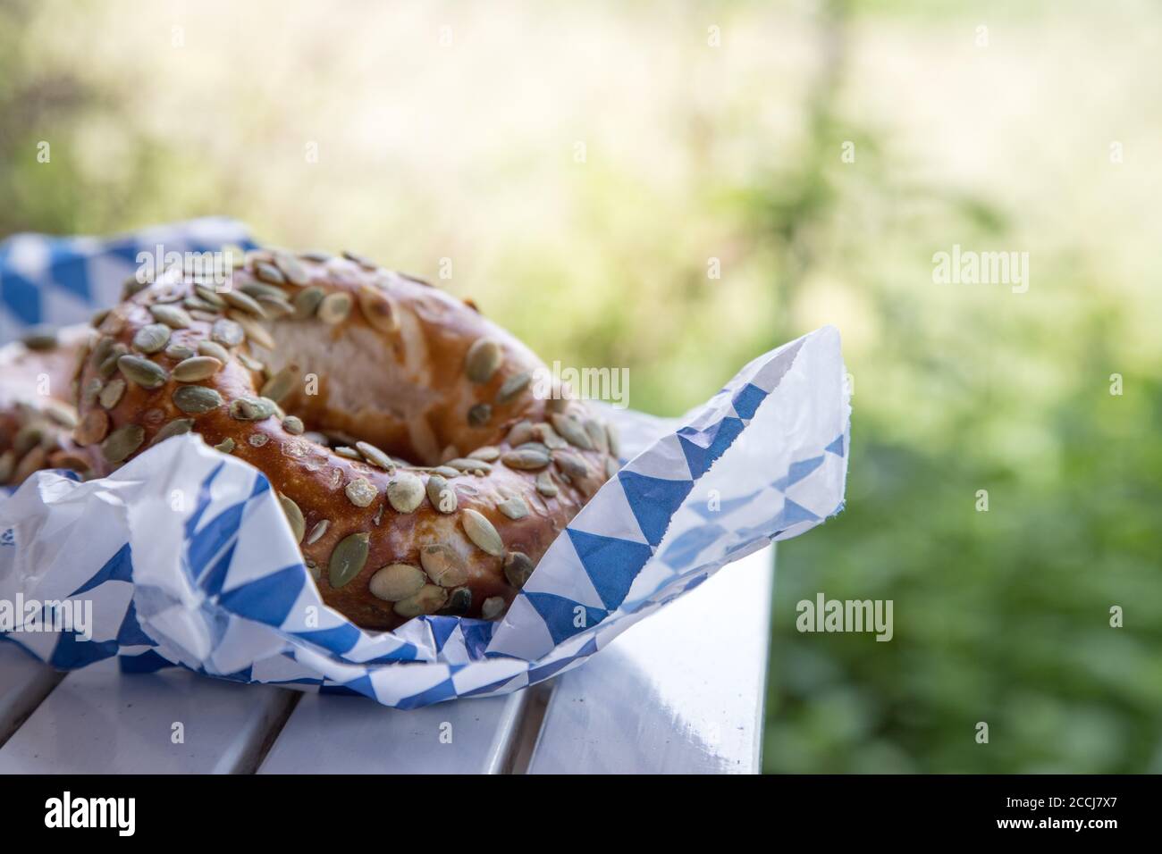 Pretzel bavaresi freschi per colazione, adagiati su un tavolo di legno all'aperto Foto Stock