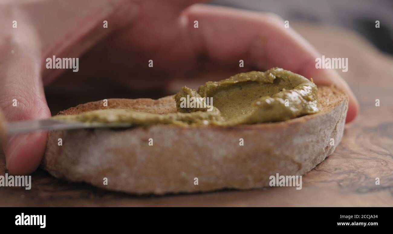 uomo spalmare crema di pistacchio sopra la ciabatta fetta closeup, foto ampia Foto Stock