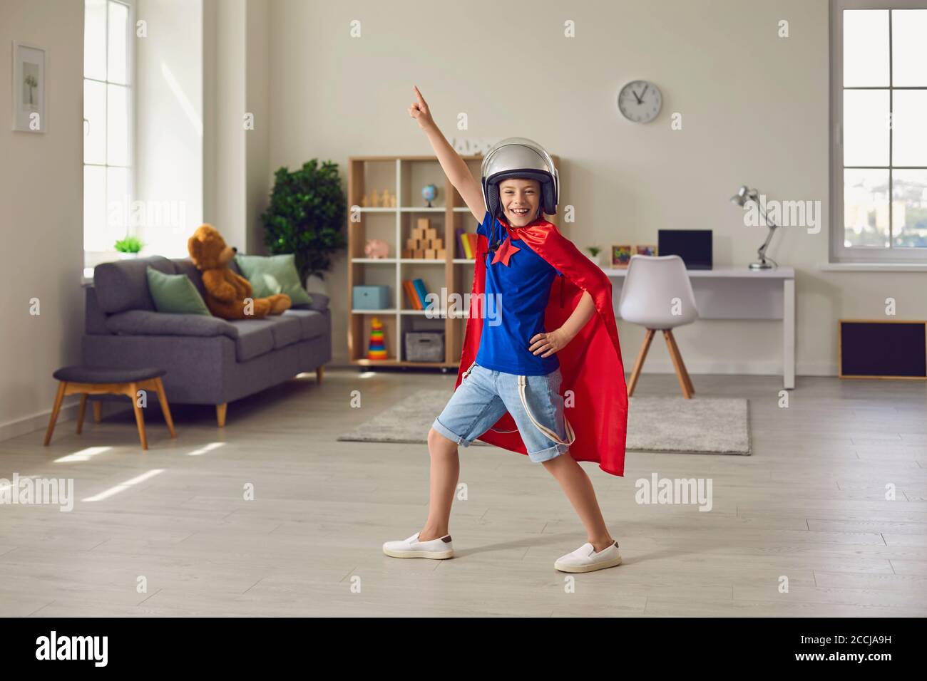 Ragazzo eroe in costume piloti e casco che gioca ruolo di supereroe a casa Foto Stock