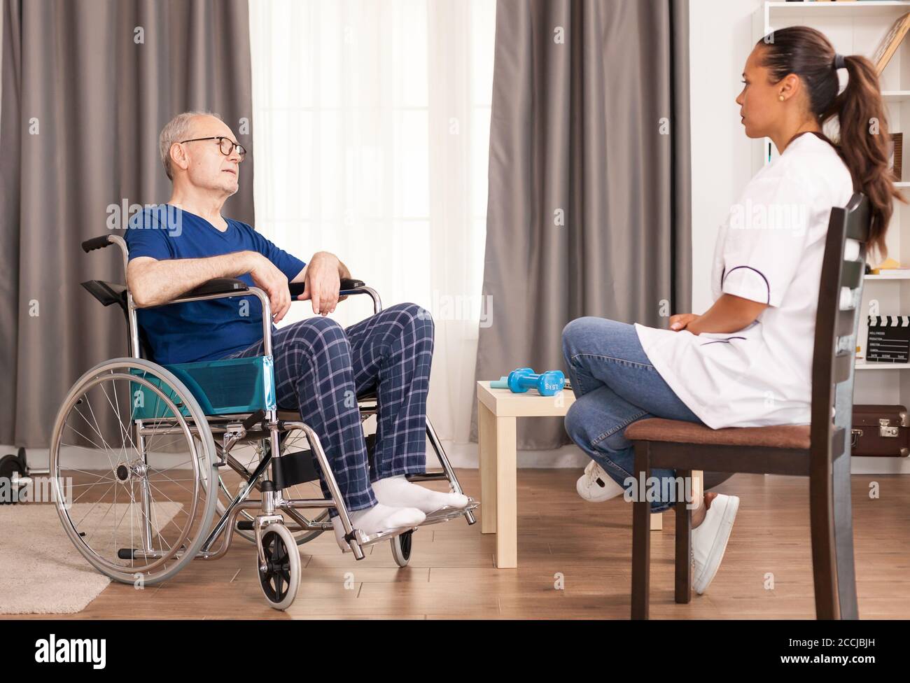 Anziano e assistente che discutono del suo incidente e del suo trattamento. Invalidità persona anziano con operatore medico in assistenza infermieristica a casa, assistenza sanitaria e medicina Foto Stock