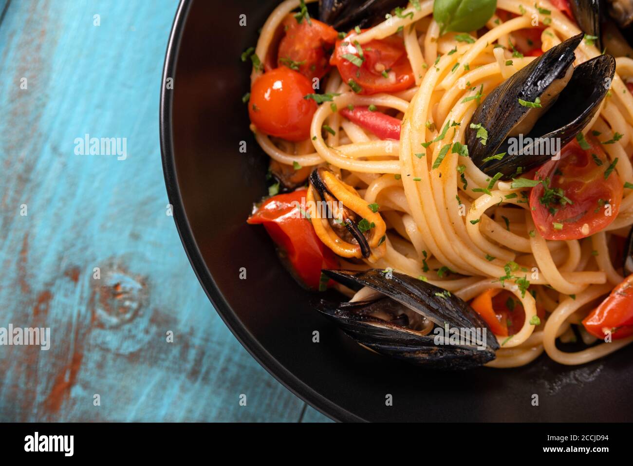 Piatto di deliziosi spaghetti con pomodori ciliegini e salsa di cozze, un tipico cibo italiano Foto Stock