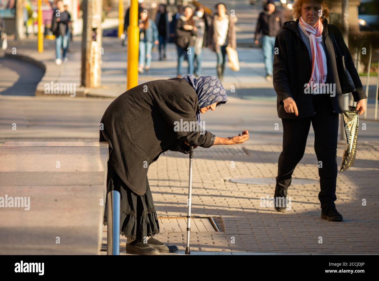 Donna anziana mendicante anziana che indossa abiti neri e tiene un bastone sta implorando denaro per le strade di Sofia Bulgaria Foto Stock