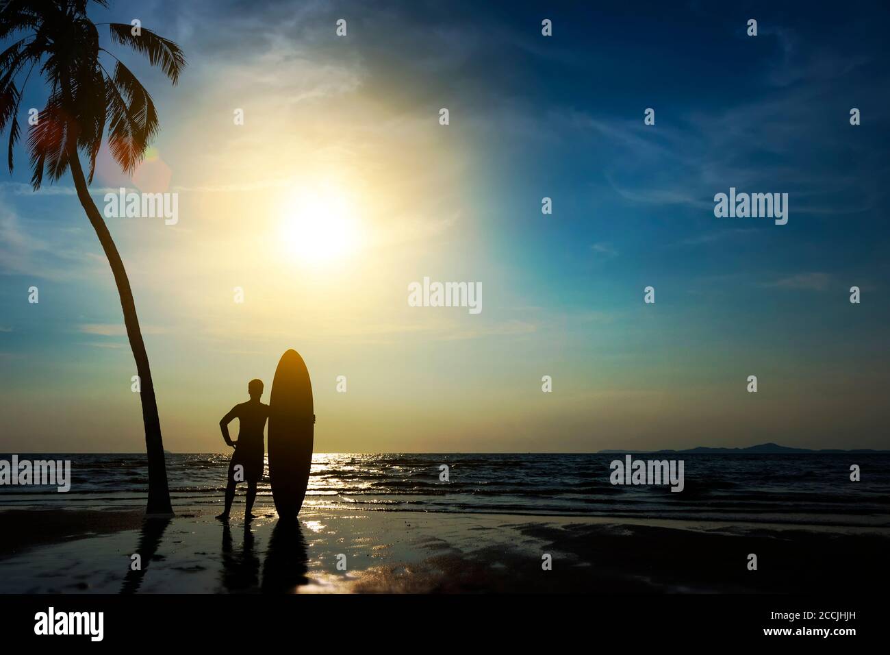 Silhouette di uomo da surf stand con una tavola da surf e palme da cocco. Surf alla spiaggia del tramonto. Sport acquatici all'aperto avventura lifestyle.Summer attività. Mano Foto Stock