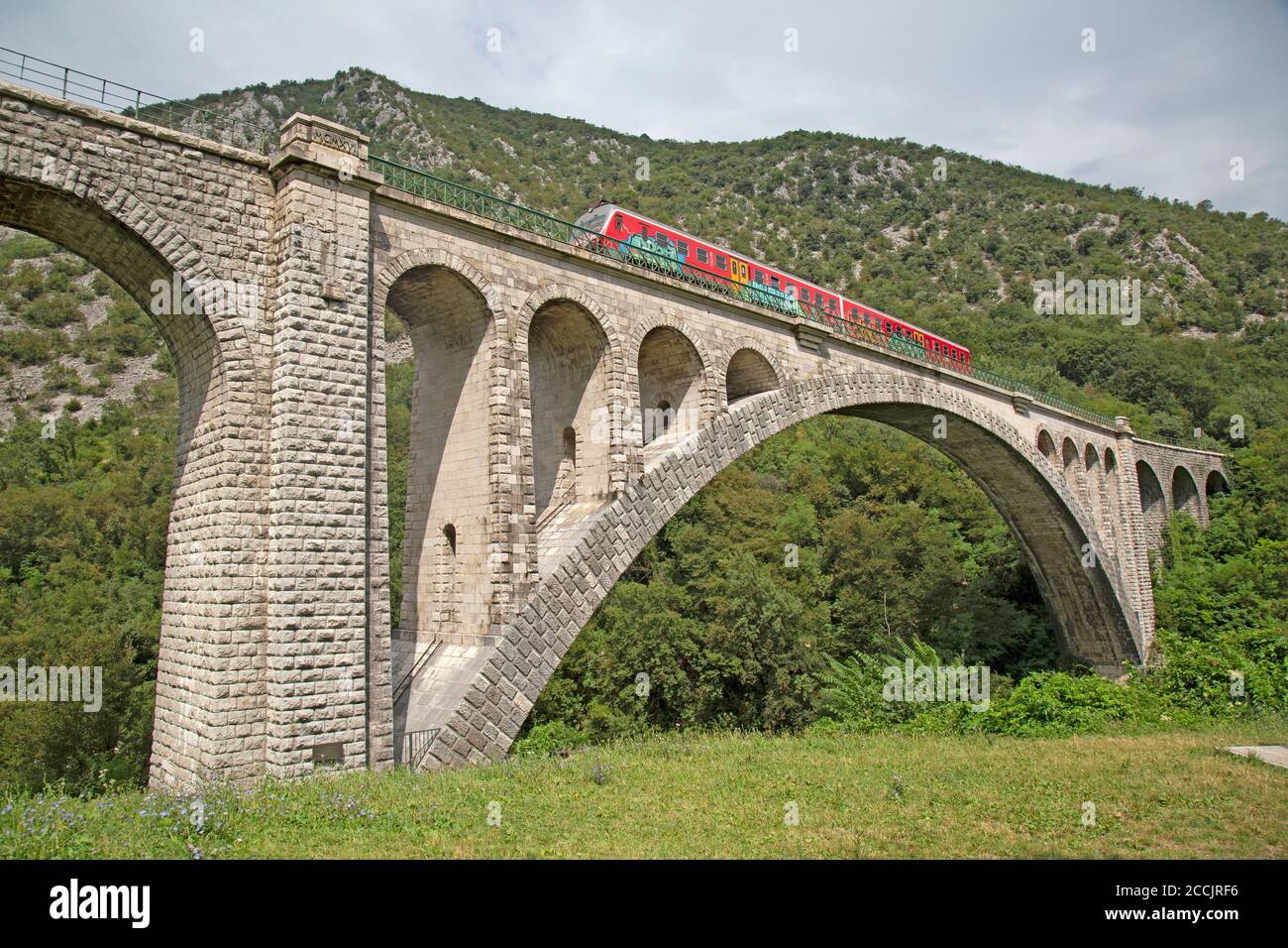 Un treno che attraversa il ponte ferroviario Solkan costruito in pietra sul fiume Soca vicino a Nova Gorica in Slovenia. Foto Stock