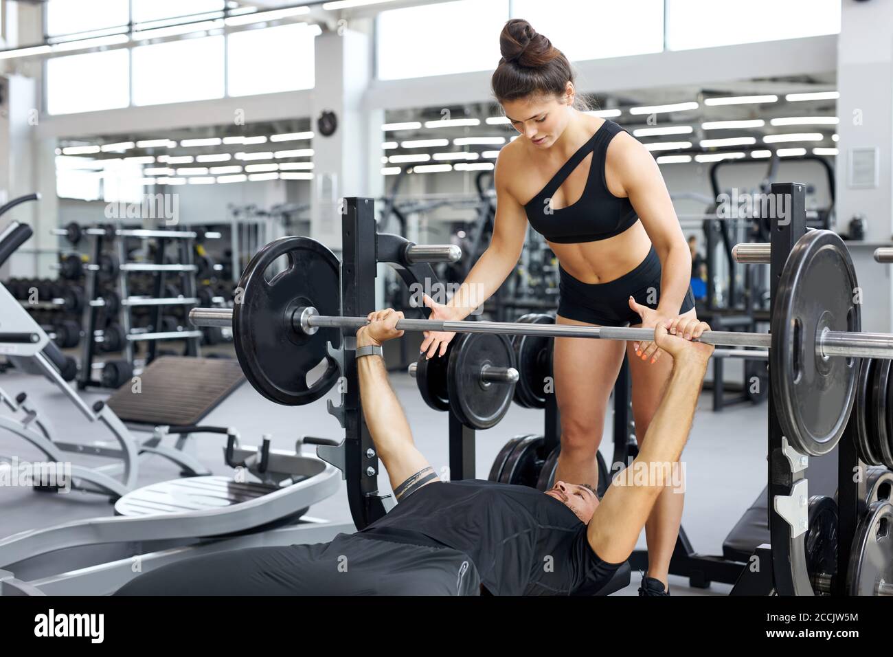 il formatore traccia la correttezza dell'esercizio in palestra, insegna alle persone a svolgere esercizi con pesi Foto Stock il formatore traccia la correttezza dell'esercizio in palestra, insegna alle persone a svolgere esercizi con pesi Foto Stock