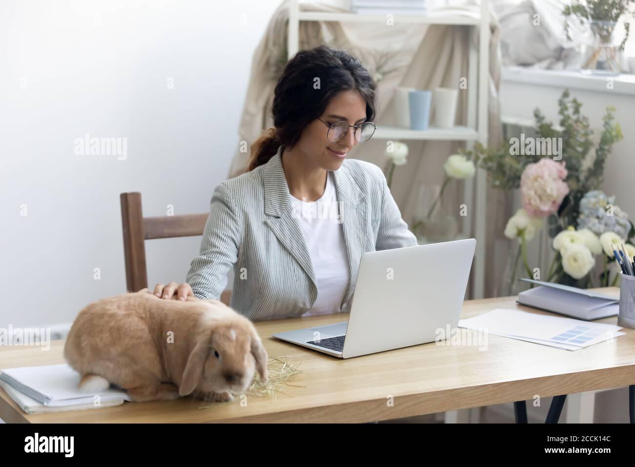 Felice giovane imprenditore femminile godendo Workday con coniglio divertente e soffice. Foto Stock