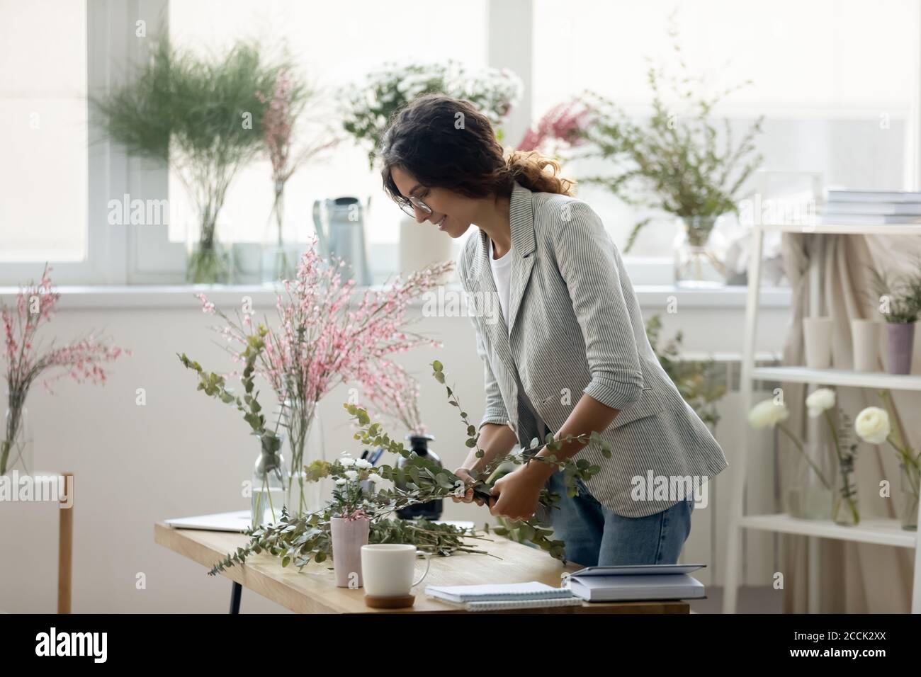 Sorridente decoratore femminile attraente che fa la composizione floreale. Foto Stock