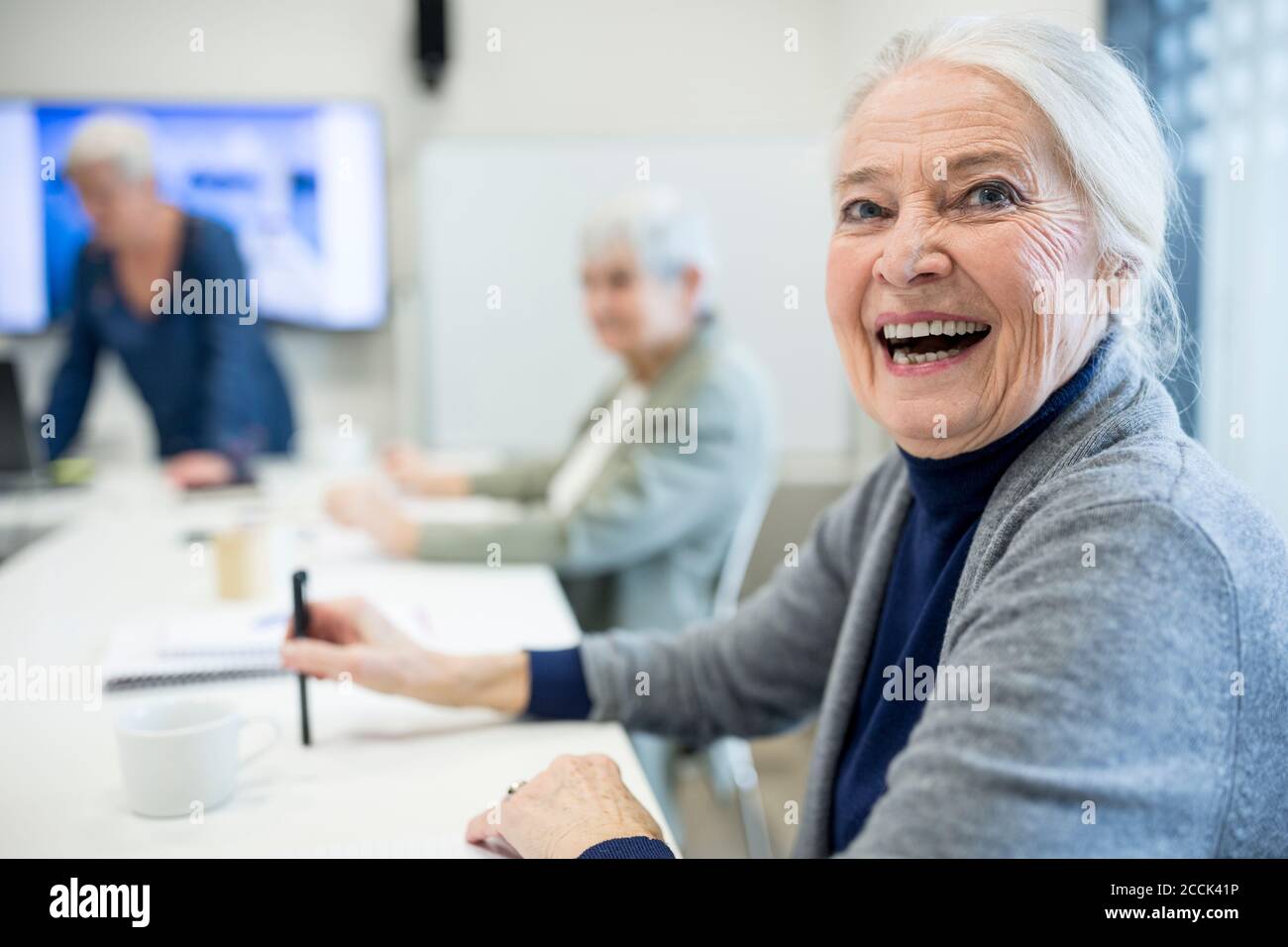 Donna anziana felice che frequenta il corso di formazione degli anziani Foto Stock