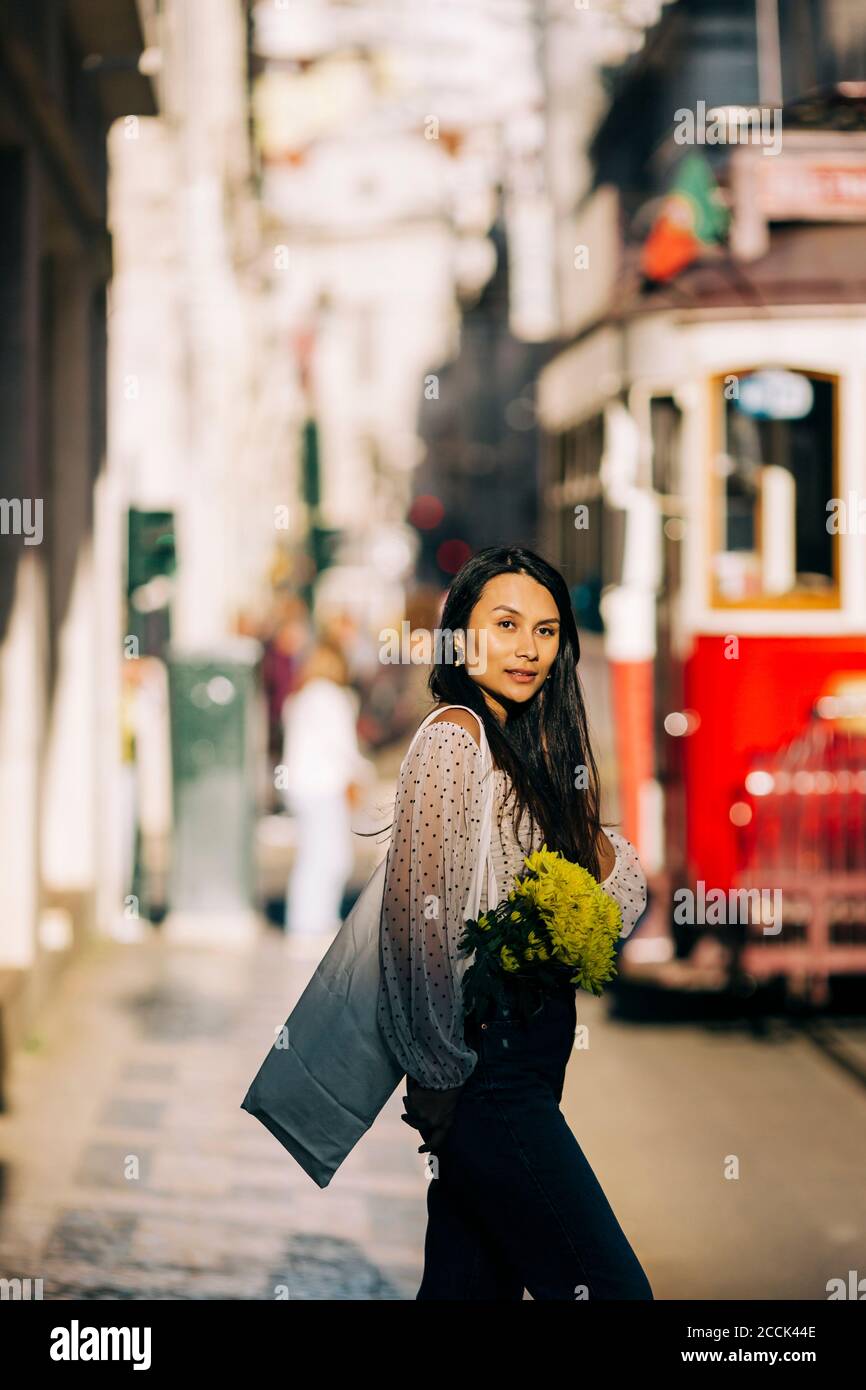 Giovane donna con bouquet che cammina in città Foto Stock