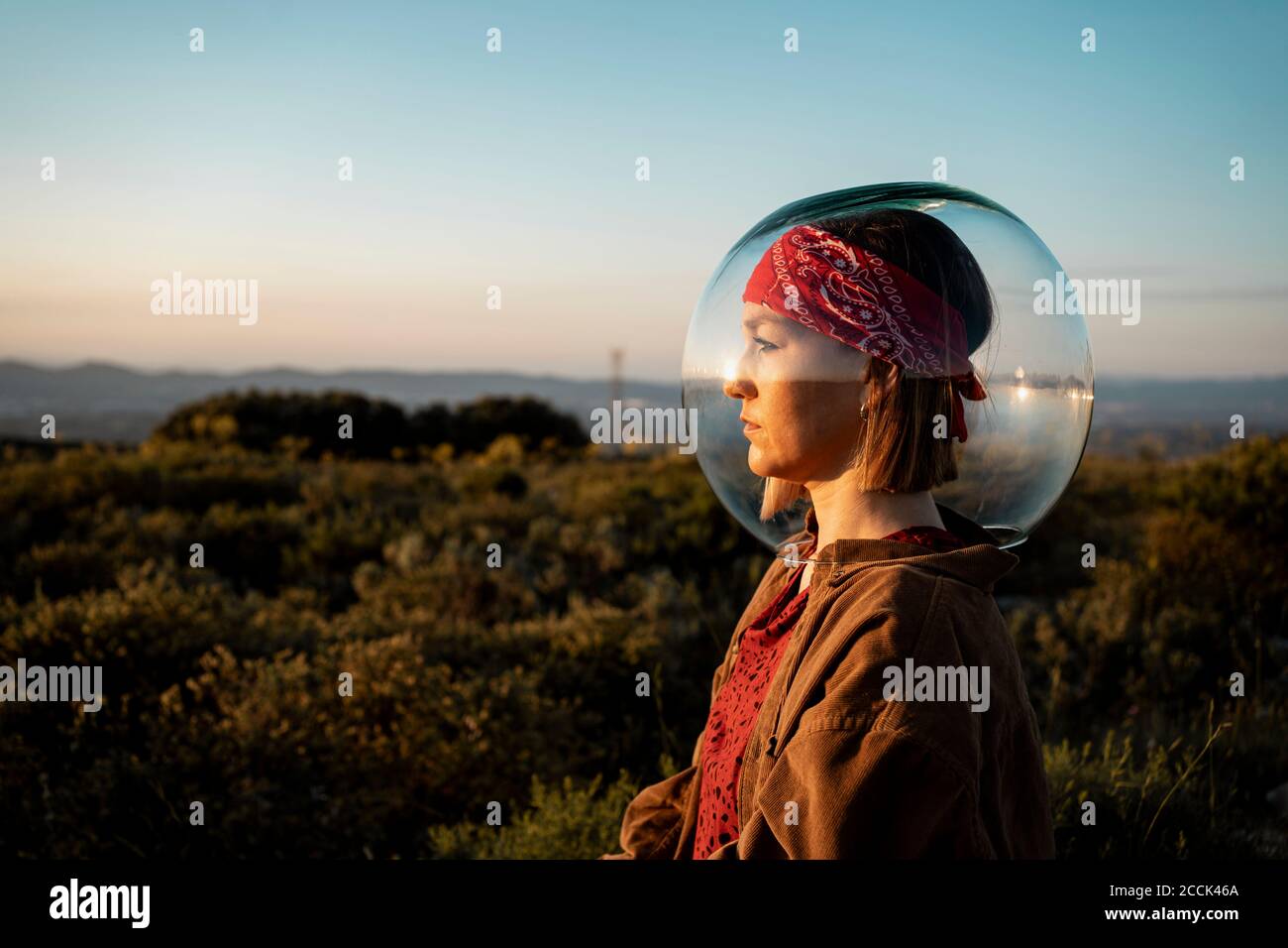 Donna con una ciotola di pesce sulla testa in campagna Foto Stock
