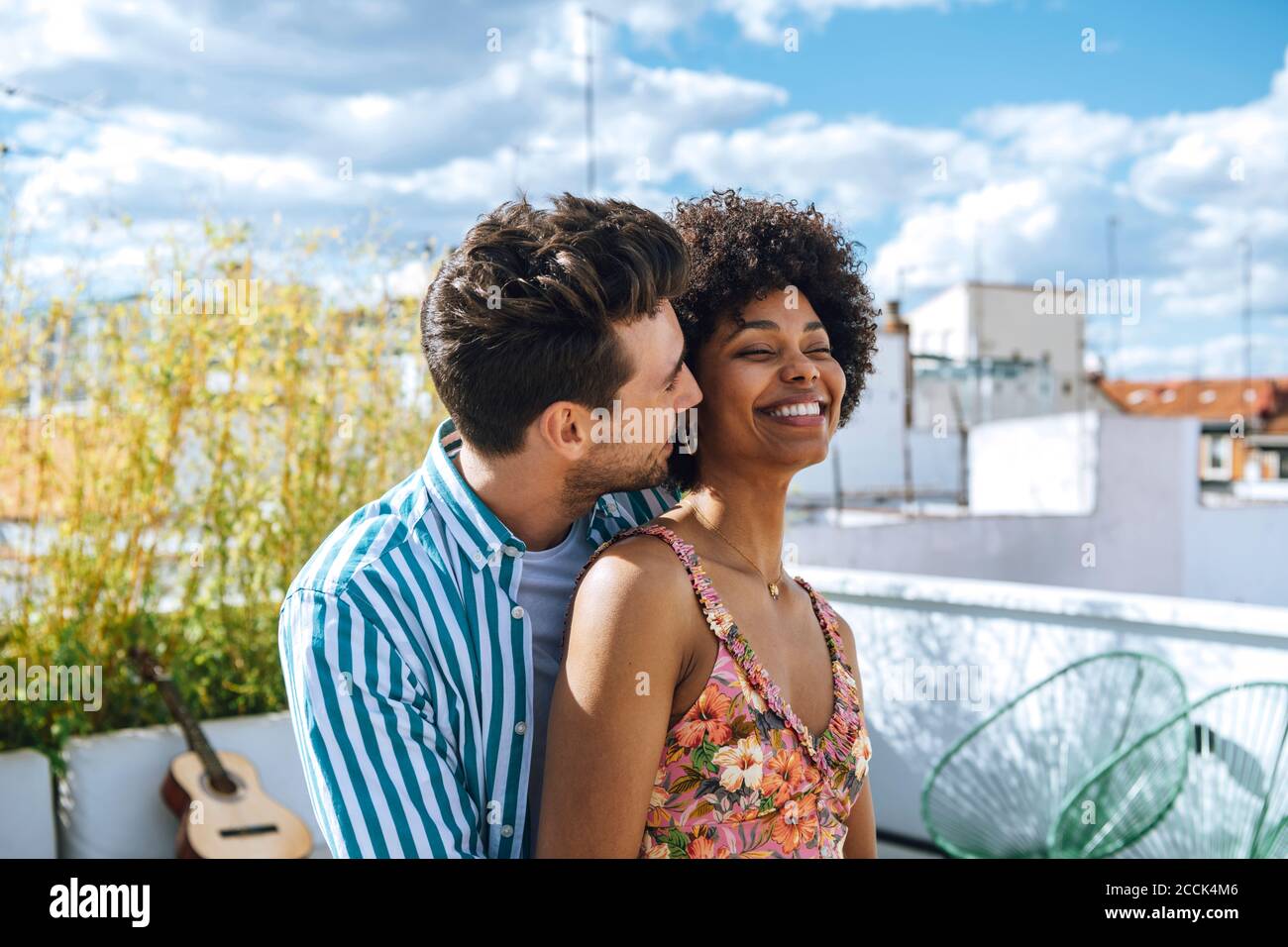Felice coppia multietnica trascorrere del tempo di qualità sul patio dell'attico Foto Stock