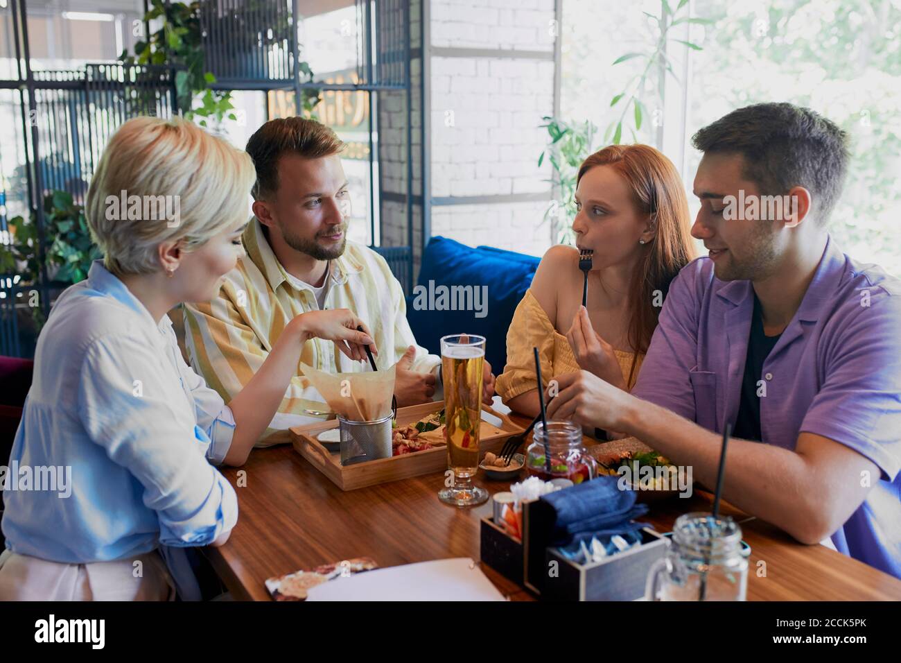 bei uomini e donne caucasici tenere una riunione amichevole in caffè, hanno un grande tempo dopo il lavoro, hanno parlare. tempo libero, bevande, persone e comunicati Foto Stock