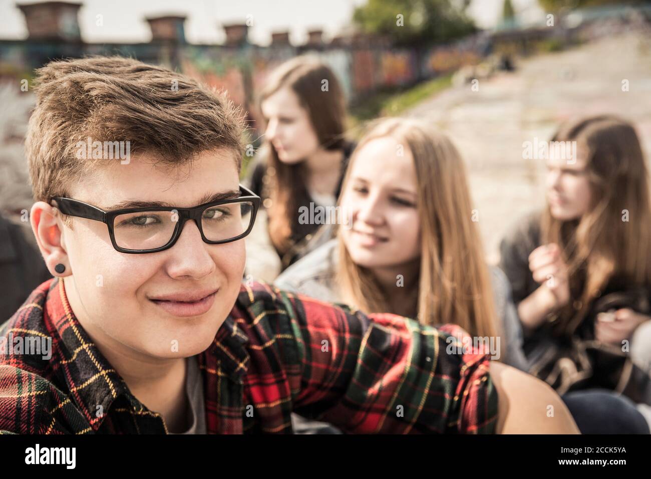 Ritratto di un adolescente sorridente che si agganava con gli amici in un vecchia zona industriale Foto Stock