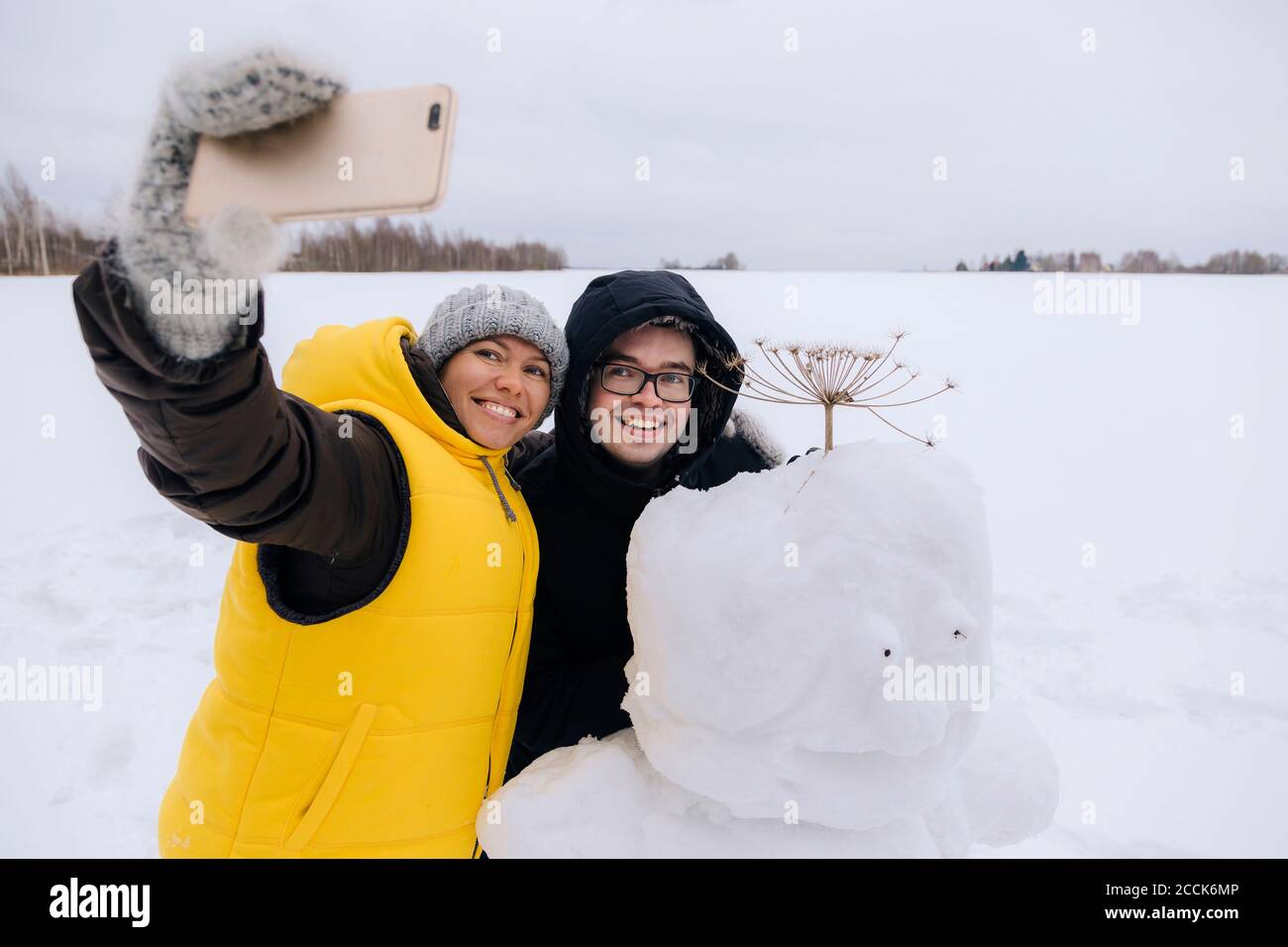 Coppia sorridente che prende selfie con pupazzo di neve Foto Stock