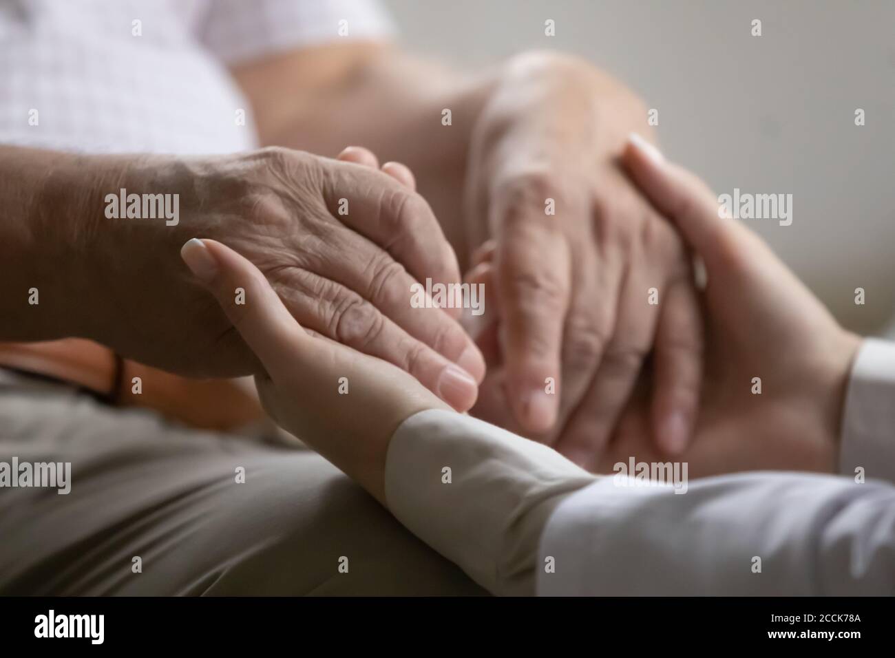 Operaio medico che tiene le mani di vecchio paziente di pensione degli anni 70. Foto Stock