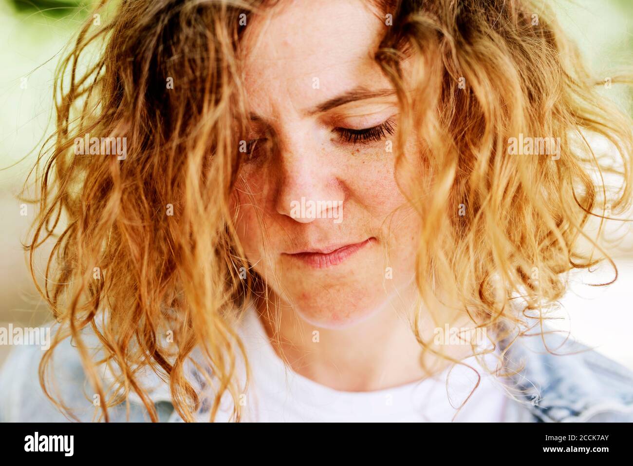 Primo piano di una donna mid adulta con capelli ondulati giù Foto Stock