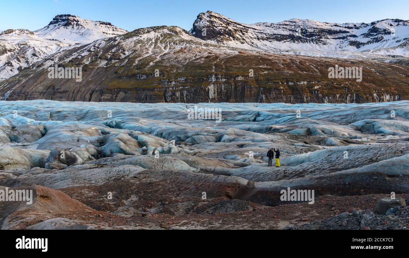 Turisti in piedi sulla lingua del ghiacciaio, Islanda Foto Stock