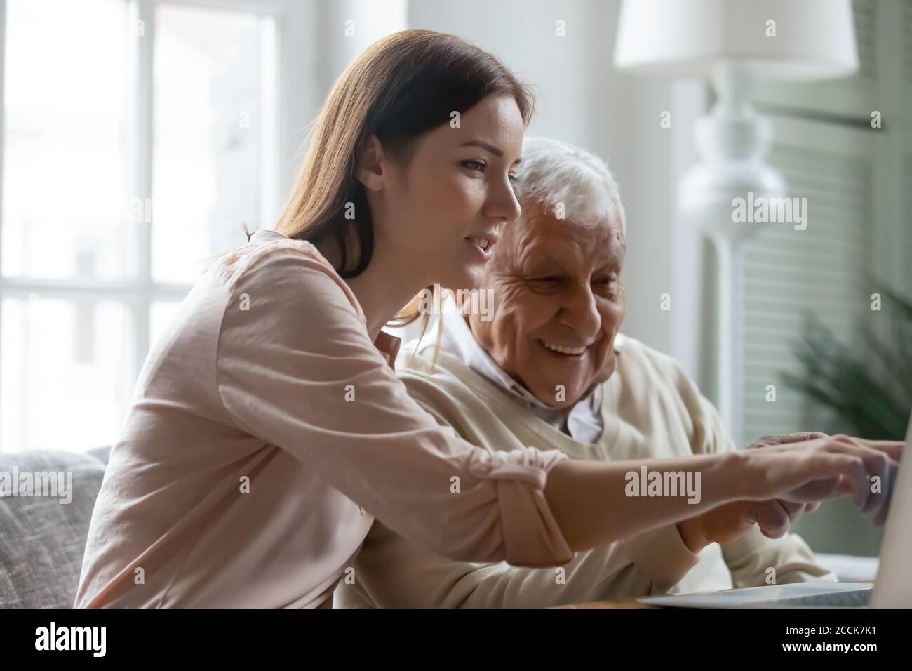 Giovane donna premurosa che mostra utili applicazioni informatiche per maturare papà. Foto Stock