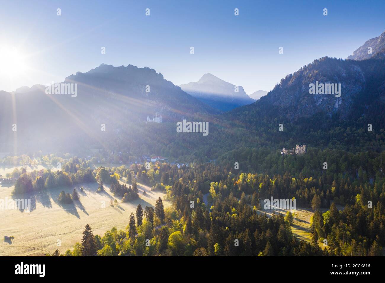 Germania, Baviera, Schwangau, Rising sole che illumina il Castello di Neuschwanstein e il Castello di Hohenschwangau Foto Stock