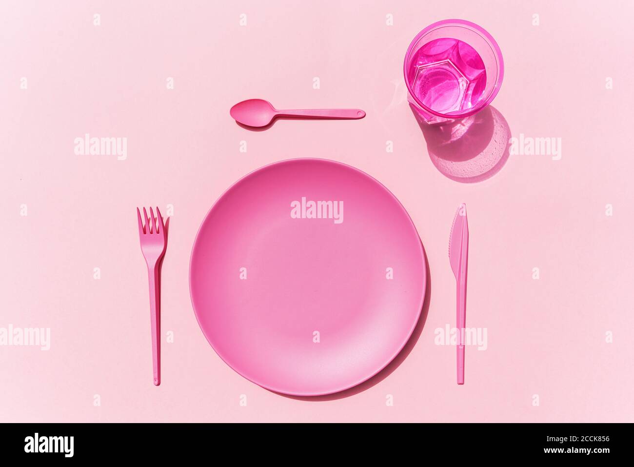 Studio di placchetta di plastica rosa, posate di plastica e bicchiere d'acqua Foto Stock
