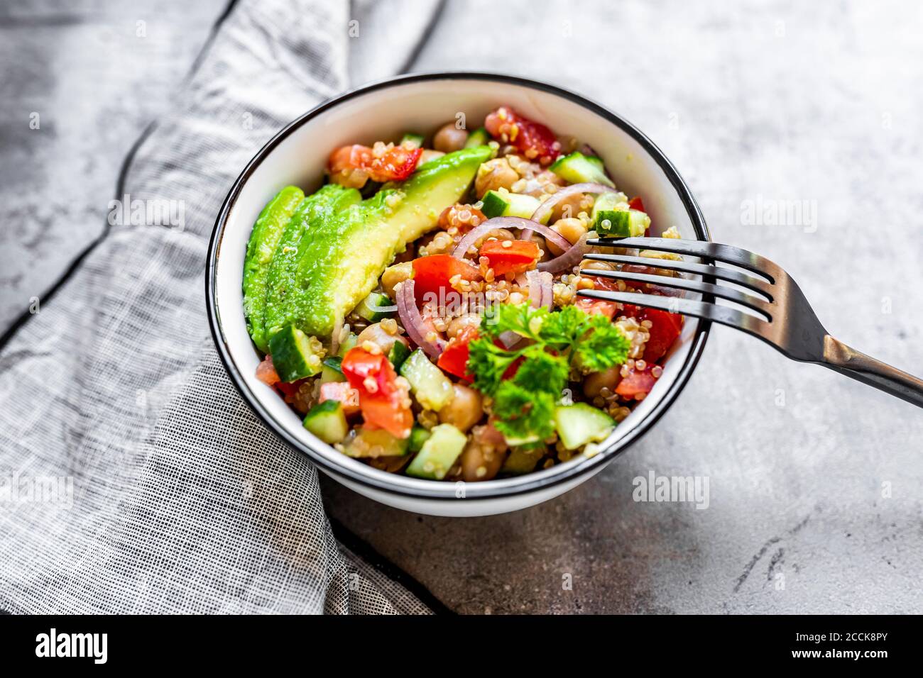 Ciotola di insalata di quinoa vegetariana con ceci, avocado, cetriolo, pomodoro, cipolla e prezzemolo Foto Stock