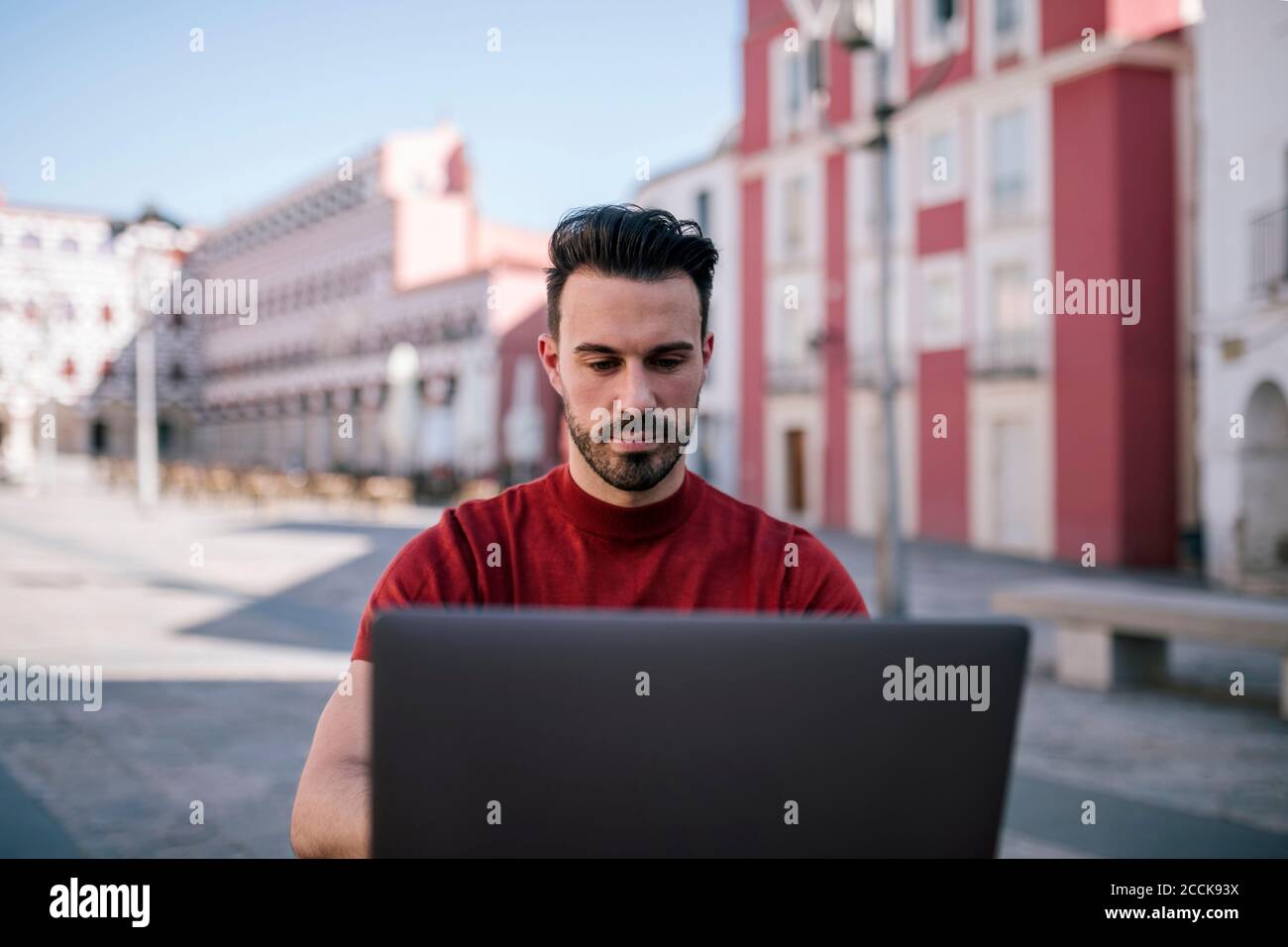 Bell'uomo che usa un computer portatile in città Foto Stock